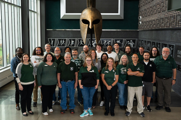 Digital Strategies and Services team members posing as a group in front of a Spartan helmet.